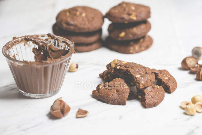 Chocolate chip cookies with hazelnuts over white table — Stock Photo