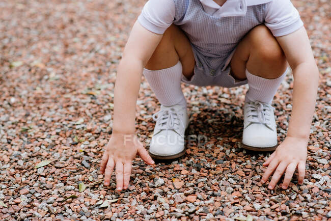 Boy crouching on a gravel driveway — Stock Photo