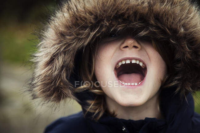 Portrait of a boy wearing a fur hood shouting — Stock Photo