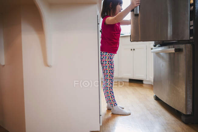 Fille regardant dans un réfrigérateur — Photo de stock