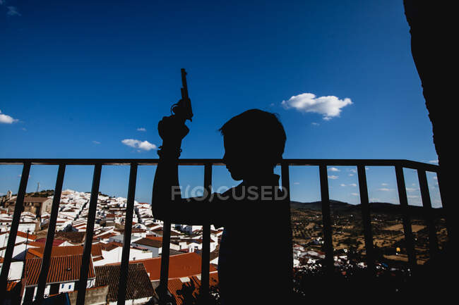 Silhueta de um menino segurando uma arma de brinquedo — Fotografia de Stock