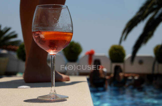 Glass of rose wine by the edge of a swimming pool at a pool party — Stock Photo