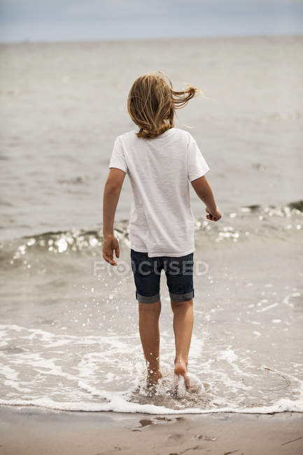Мальчик с длинными волосами гребешком в море — стоковое фото