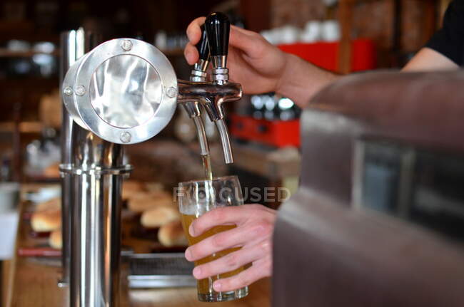 Человек тянет пинту пива в баре — стоковое фото
