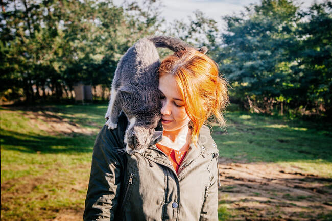 Chica de pie con un gato sobre sus hombros, Viscri, Brasov, Rumania - foto de stock