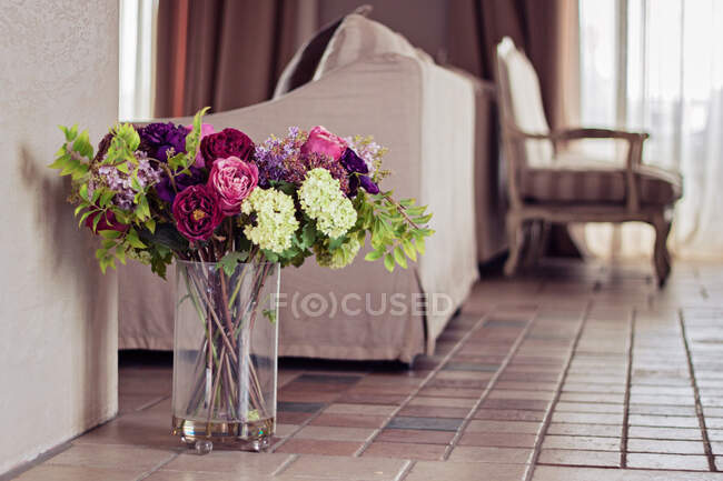 Vase rempli de fleurs artificielles dans un salon — Photo de stock