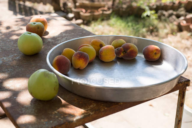 Metal tray of peaches and apples on a table — Stock Photo