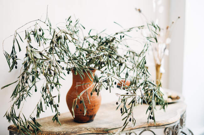 Branches in a vase with a candle on a sideboard table — Stock Photo