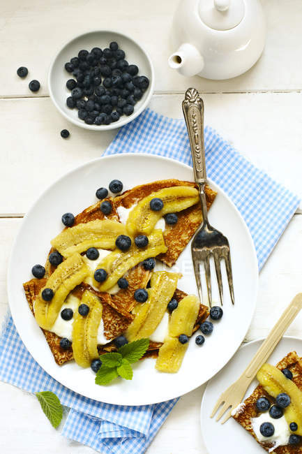 Crepes with bananas, blueberries and yogurt, closeup view — Stock Photo