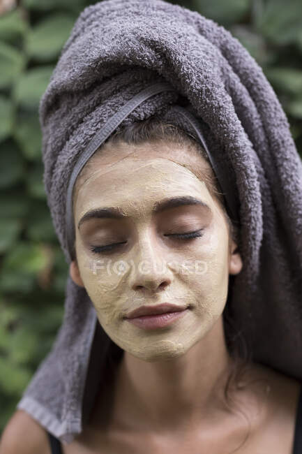 A young woman wearing a grey head towel is preparing for her facemask after a shower in a tropical balinese villa. - foto de stock