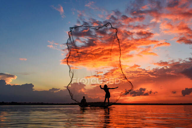 Silluez pêcheur et bateau dans la rivière sur pendant le coucher du soleil, pêcheur trottant les filets sur pendant le coucher du soleil, pendant le coucher du soleil, Thaïlande — Photo de stock