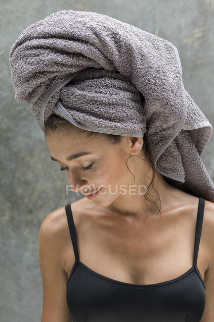 A young woman wearing a grey head towel is preparing for her facemask after a shower in a tropical balinese villa. — Stock Photo