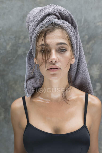 A young woman wearing a grey head towel is preparing for her facemask after a shower in a tropical balinese villa. - foto de stock