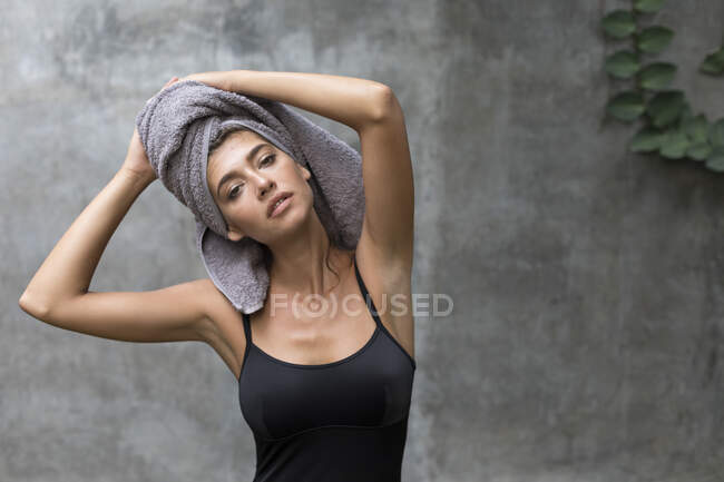 A young woman wearing a grey head towel is preparing for her facemask after a shower in a tropical balinese villa. — Stock Photo
