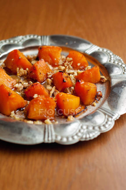 Baked pumpkin with walnuts and honey on metal plate — Stock Photo