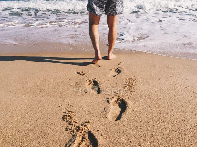 Hombre caminando hacia el océano surf - foto de stock