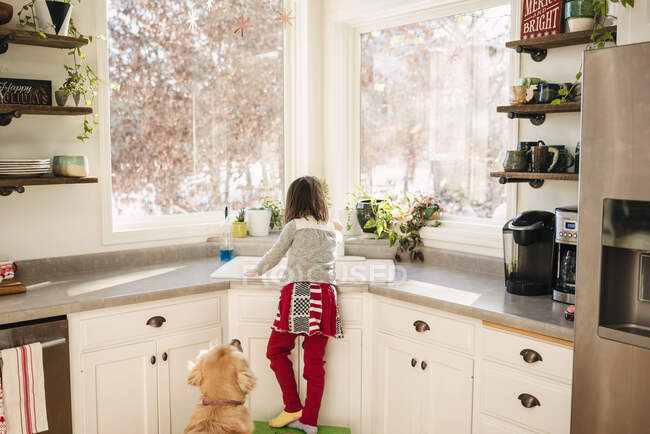 Young girl washing dishes at sink — Stock Photo