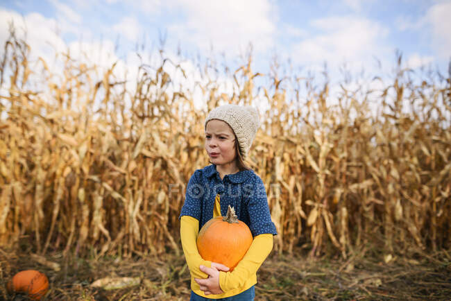 Jeune fille portant des citrouilles dans un patch de citrouille — Photo de stock