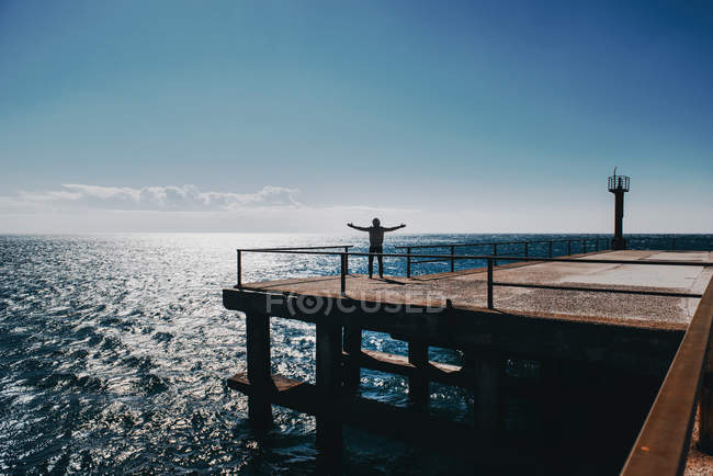 Man standing on a pier with his arms outstretched — Stock Photo