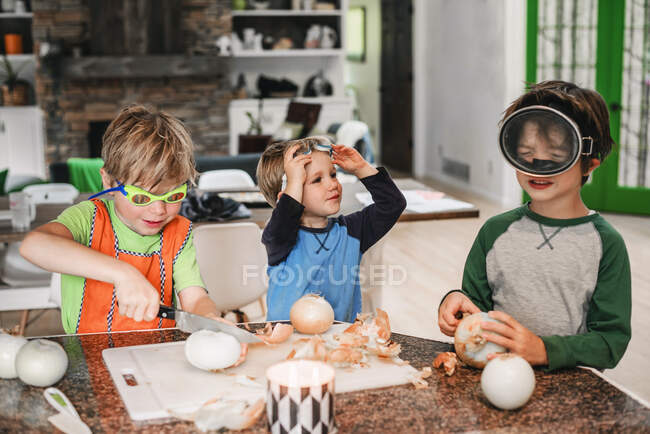 Троє дітей допомагають готувати на кухні. — стокове фото