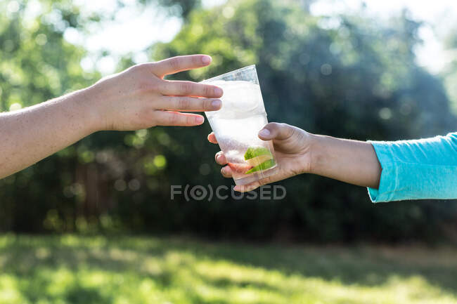 Обрезанный снимок человека, дающего стакан лимонада другому человеку — стоковое фото