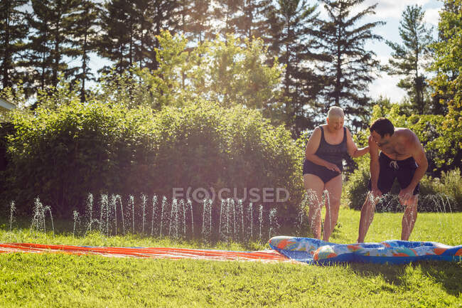 Man and senior woman playing on slip and slide — Stock Photo