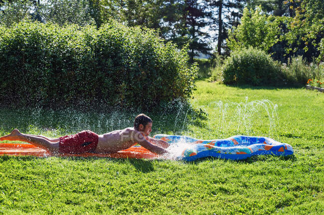 Mid adult man playing on slip and slide — Stock Photo