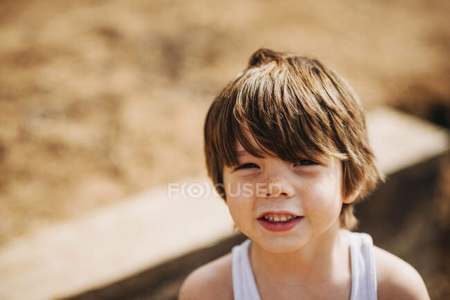 Young boy at beach with sand on his face — Stock Photo