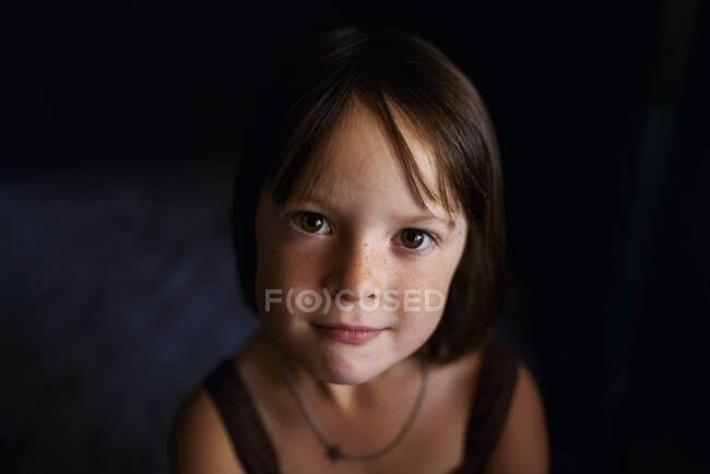 Portrait of a smiling girl on dark background — Stock Photo