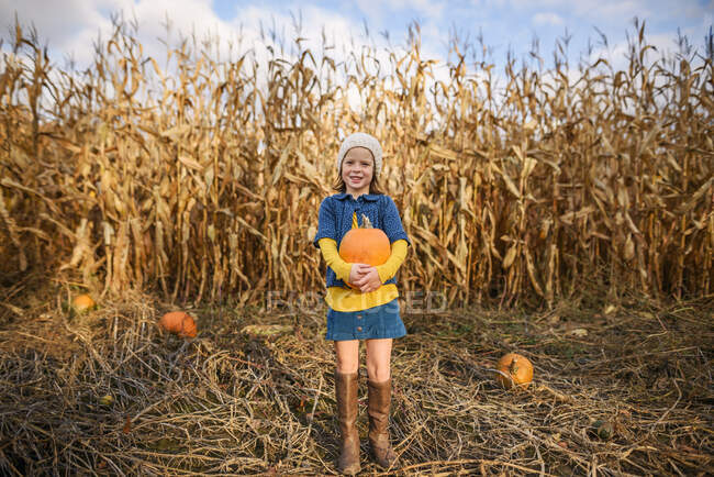 Junges Mädchen trägt Kürbisse in einem Kürbisfeld — Stockfoto