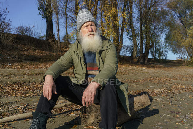 Старик смотрит на закат у реки — стоковое фото