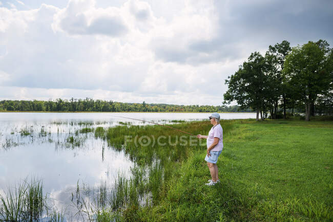 Donna anziana pesca in un lago — Foto stock