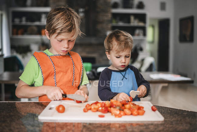 Двоє маленьких дітей допомагають готувати на кухні — стокове фото