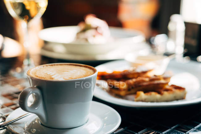 Чашка гарячої кави та печива над дерев'яним столом, вид крупним планом — стокове фото