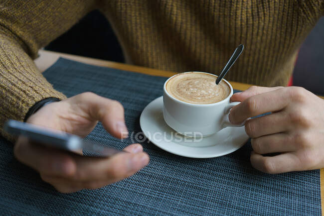 Homme d'affaires utiliser téléphone mobile et tasse de café ton sombre. — Photo de stock