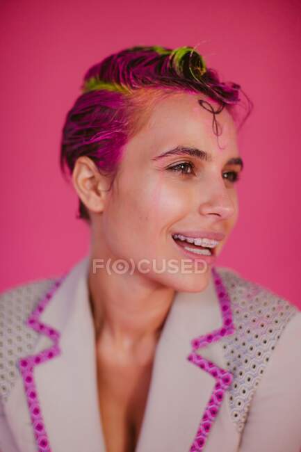 Retrato de una mujer sonriente con cabello rosa y tirantes - foto de stock