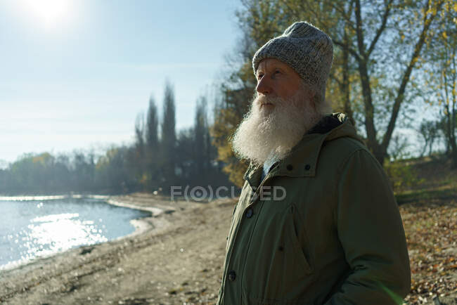 Old man looks at sunset next to river — Stock Photo