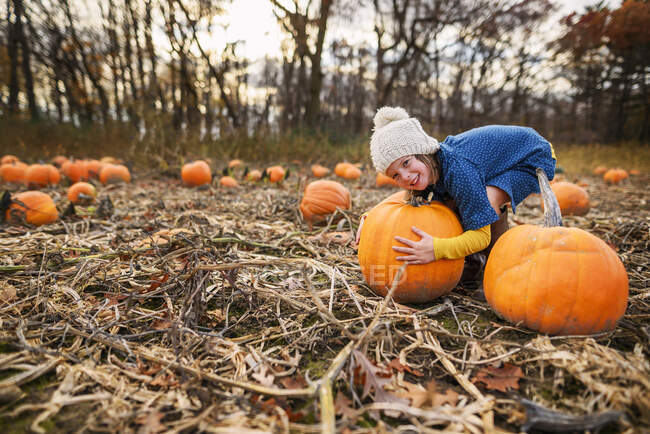 Young girl carrying pumpkins in a pumpkin patch — Stock Photo