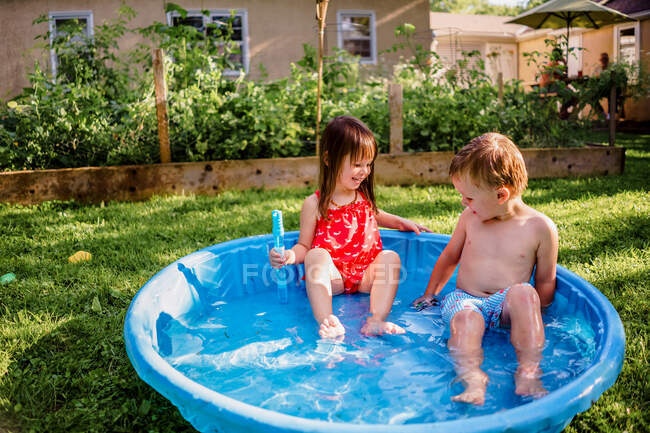 Two young children playing in small kiddie pool in the summer — Stock Photo