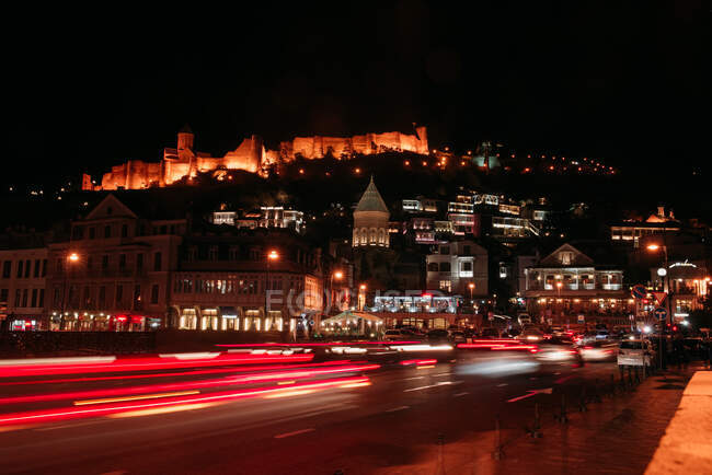 Urban night view of road traffic with castle on background — Stock Photo