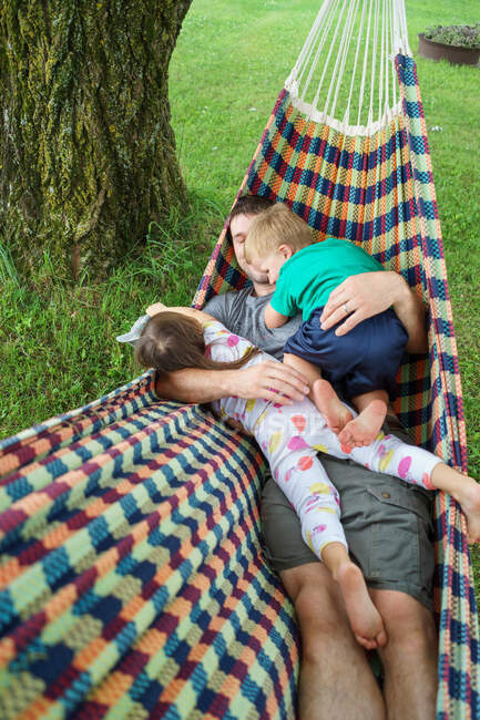 Батько грає з двома маленькими дітьми на гамаку — стокове фото