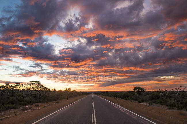 Живописный вид на сельскую дорогу под драматическим небом, Западная Австралия, Австралия — стоковое фото