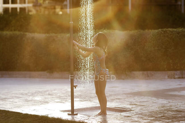 Chica de pie bajo una ducha pública en un parque - foto de stock