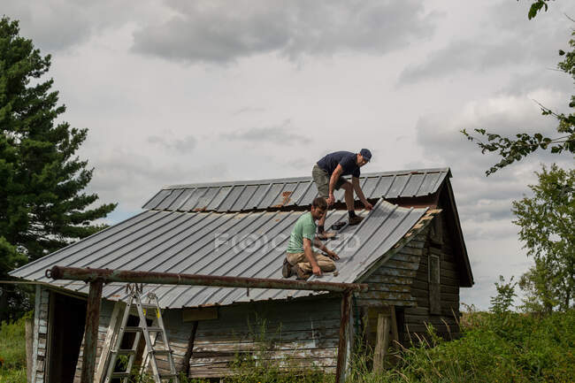 Dois homens a trabalhar no telhado do velho barracão — Fotografia de Stock