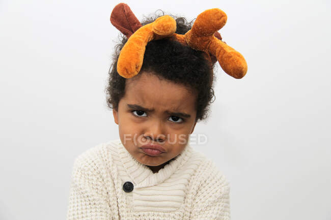 Retrato de un chico tirando caras raras usando cuernos de Navidad - foto de stock