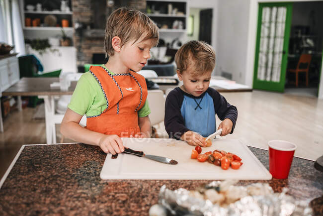 Двоє маленьких дітей допомагають готувати на кухні. — стокове фото