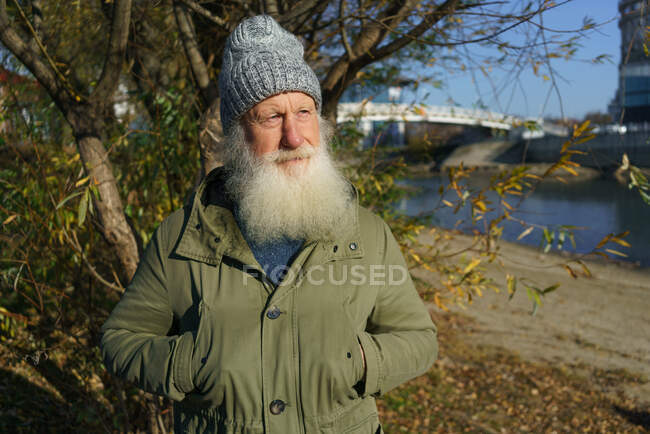 Old man looks at sunset next to river — Stock Photo