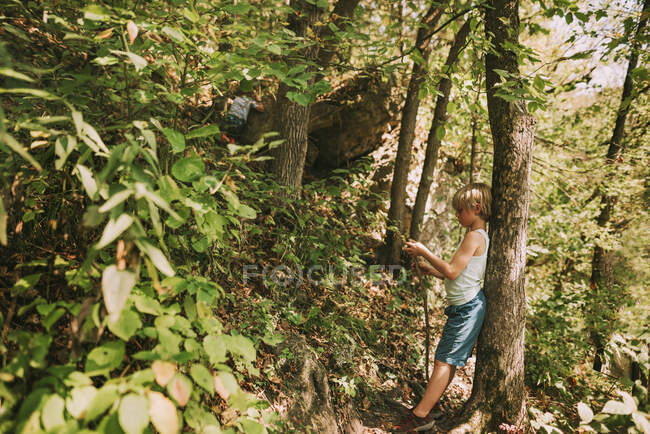 Jovem encostado à árvore na floresta — Fotografia de Stock