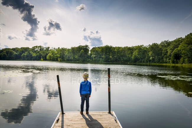 Young boy standing on dock by lake on nature — Fotografia de Stock