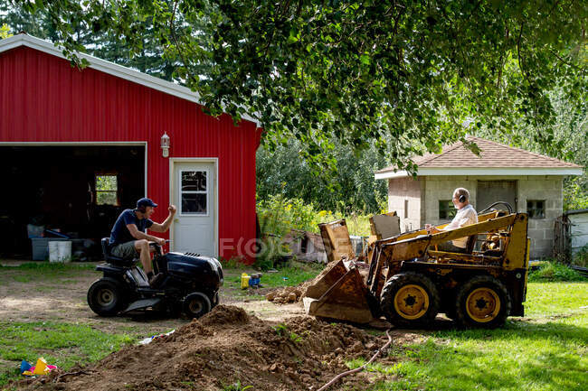 Adult father and son head to head with skidsteer — Stock Photo